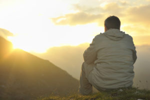 man using the steps to meditating on mountainside