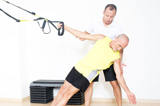 coach helps elderly man with trx single arm bicep curl