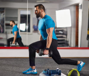 man doing lunge with dumbbells at home workouts for men