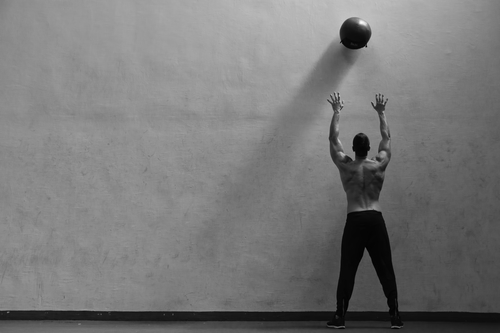 man throwing medicine ball against the wall power workout for men