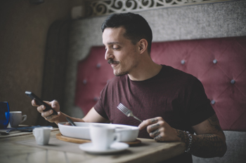 man having breakfast with mobile phone in cafeteria stress hacks
