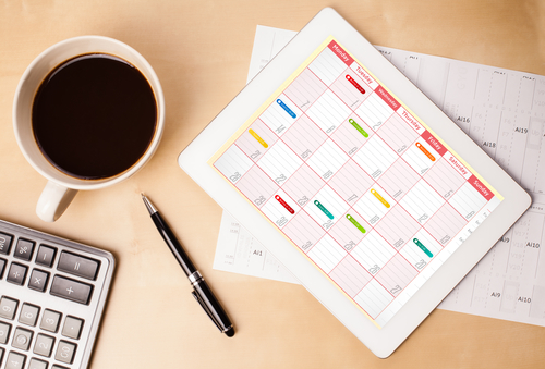 motivation for men tablet pc showing calendar and a cup of coffee on a wooden work table close-up